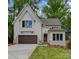 Charming two-story home featuring a gabled roof, wood garage door, and nicely landscaped front yard at 1807 Arnold Dr, Charlotte, NC 28205
