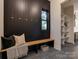 A stylish mudroom with a wooden bench, black paneling, and stone tile flooring at 1807 Arnold Dr, Charlotte, NC 28205