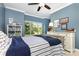 Blue bedroom with a nice window view, white trim, ceiling fan, and a nicely decorated bookshelf at 209 Helton Ln, Fort Mill, SC 29708