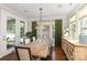 Dining room with rustic wood table, chandelier, light hardwood flooring, large windows and green curtains at 209 Helton Ln, Fort Mill, SC 29708
