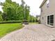 View of the backyard with a brick patio and built-in fire pit with mature landscaping at 2369 Baxter Se Pl, Concord, NC 28025