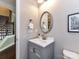 Half bath with a gray vanity, an oval mirror, and a stairway in the background at 2369 Baxter Se Pl, Concord, NC 28025