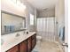 Bright bathroom featuring a decorative mirror, neutral tile floors, and a shower with a striped curtain at 2369 Baxter Se Pl, Concord, NC 28025