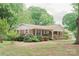 Inviting brick home featuring a covered porch, complemented by mature trees and vibrant flowerbeds at 2412 Wedgewood Dr, Salisbury, NC 28146