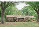 Charming brick home with covered porch and carport, surrounded by lush trees and landscaping at 2412 Wedgewood Dr, Salisbury, NC 28146