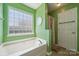 Bright bathroom featuring a tub with tile surround, unique window, and tiled flooring at 3038 Twin Peaks Ct, Monroe, NC 28110
