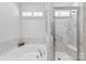 Bathroom featuring a soaking tub and a tiled shower with glass door and overhead window at 329 Brambling Ct, Wesley Chapel, NC 28110