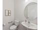 Powder room with pedestal sink, round mirror, framed starfish art, and modern fixtures enhancing the minimalist aesthetic at 329 Brambling Ct, Wesley Chapel, NC 28110