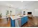 Open kitchen with blue island, stainless steel appliances, and hardwood floors, flowing into the living area at 404 Basingdon Ct, Waxhaw, NC 28173