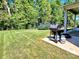 Well-maintained backyard with a gas grill on a concrete patio and a trampoline on the lawn at 413 Hunton Forest Dr, Concord, NC 28027