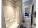 This bathroom features a clean white shower-tub combo next to a doorway leading to the bedroom at 413 Hunton Forest Dr, Concord, NC 28027