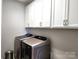 This laundry room features modern washer and dryer units with bright white cabinets above at 413 Hunton Forest Dr, Concord, NC 28027