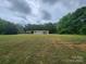 Expansive lawn surrounds this cozy single-story home with a storage shed; trees provide a scenic backdrop at 544 Bentley Rd, Shelby, NC 28152