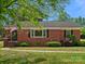 Charming one-story brick home featuring a well-maintained lawn and mature landscaping, American flag near entry at 613 W Pine St, Kershaw, SC 29067
