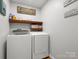 A modern laundry room equipped with a washer, dryer, and shelving for storage at 613 W Pine St, Kershaw, SC 29067