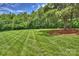 Well-manicured backyard with lush grass, tall trees and landscaping at 6723 Joliette Ln, Charlotte, NC 28277