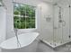 Bright and luxurious bathroom featuring a soaking tub, glass shower, large window, and sleek, contemporary design at 6723 Joliette Ln, Charlotte, NC 28277