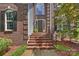 Elegant brick entryway with a solid wood door and decorative landscaping at 6723 Joliette Ln, Charlotte, NC 28277