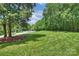 Expansive front lawn features lush grass and mature trees, creating a serene and inviting landscape at 6723 Joliette Ln, Charlotte, NC 28277