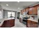A well-lit kitchen with dark cabinets, marble flooring, stainless steel appliances and an eat-in area at 735 Shuttles Way, Fort Mill, SC 29715