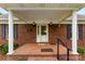Inviting front porch with brick flooring, white columns, and black shuttered windows at 102 Sussex Ave, Cherryville, NC 28021