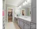 Elegant bathroom featuring dual sinks, a vanity area, white tile flooring, and a walk-in closet at 1045 Spyglass Ln, Waxhaw, NC 28173