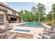 Relaxing backyard retreat featuring a lovely pool, fire feature, plenty of seating, and lush trees at 1045 Spyglass Ln, Waxhaw, NC 28173