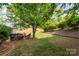 Lush backyard with mature trees, featuring a patio area with outdoor seating and ample green space at 13406 Ada Ct, Charlotte, NC 28213