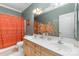 Bright bathroom with a double vanity, an orange shower curtain, and a large mirror at 13406 Ada Ct, Charlotte, NC 28213
