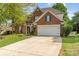 Charming brick two-story home featuring a well-manicured lawn, landscaping, and a long driveway at 13406 Ada Ct, Charlotte, NC 28213