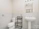 Bathroom with tiled walls, a pedestal sink, and a toilet with storage shelves behind it at 14834 Pawnee Trl, Matthews, NC 28104
