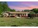 Charming brick home with a well-maintained lawn, flowering shrubs, and classic black shutters at sunset at 14834 Pawnee Trl, Matthews, NC 28104