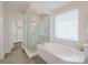 Bright bathroom featuring a soaking tub, walk-in shower with glass door, and a window at 15431 Cimarron Hills Ln, Charlotte, NC 28278