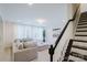 Cozy living room with stair access, neutral furnishings, and soft natural light from large windows at 15431 Cimarron Hills Ln, Charlotte, NC 28278