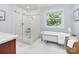 Bright bathroom featuring a soaking tub, glass-enclosed shower, and marble tile at 1721 White Pond Ln, Waxhaw, NC 28173