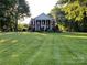 Stately brick home with white columns and expansive lawn framed by mature trees exudes elegance and charm at 1721 White Pond Ln, Waxhaw, NC 28173
