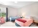 Bright bedroom with two beds, carpet, a window with a curtain, and a red rocking chair at 18027 Train Station Dr, Cornelius, NC 28031