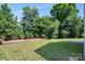 Spacious backyard with a large wooden deck and green grass, shaded by mature trees at 2751 Bramble Ridge Ct, Charlotte, NC 28215