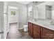 Bathroom featuring double sinks, wood-look floors, and a large mirror with shower view at 2751 Bramble Ridge Ct, Charlotte, NC 28215