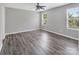 A bright bedroom with wood-look floors, a ceiling fan, and two windows at 2751 Bramble Ridge Ct, Charlotte, NC 28215