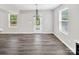 Bright dining area with three windows, wood floors, modern chandelier, and access to the backyard at 2751 Bramble Ridge Ct, Charlotte, NC 28215