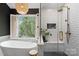 Elegant bathroom features a freestanding tub, a modern shower with subway tile, and a serene backyard view at 3134 Old Chapel Ln, Charlotte, NC 28210