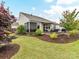Lush backyard featuring a stone-accented patio area, privacy fence, mature trees, and well-manicured landscaping at 3333 Oliver Stanley Trl, Lancaster, SC 29720