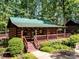 Inviting log cabin with green metal roof, wooden porch, and well-maintained landscaping at 3333 Oliver Stanley Trl, Lancaster, SC 29720