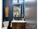 Chic half-bathroom with dark blue accent wall, decorative mirror, and wood-grain cabinet at 444 Starnes Circle Dr, Taylorsville, NC 28681