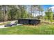 Modern black house surrounded by lush greenery, featuring a flat roof, and a long driveway at 444 Starnes Circle Dr, Taylorsville, NC 28681