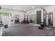The home gym features rubber flooring, several weight training machines, mirrors, and natural light from the window at 444 Starnes Circle Dr, Taylorsville, NC 28681
