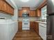 Functional kitchen featuring wooden cabinets, white appliances, and durable wood-look flooring at 4609 Coronado Dr, Charlotte, NC 28212