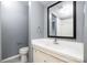 Bathroom includes a vanity with sink and mirror, toilet, and towel ring on gray walls at 4609 Coronado Dr # N, Charlotte, NC 28212