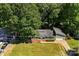 Aerial view of a charming green home with an attached garage, surrounded by a lush lawn and abundant, mature trees at 619 Archibald Rd, Concord, NC 28025